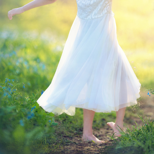 Legs of a girl walking on a wooden bridge in the middle of the ocean moving away towards the horizon in the sea
